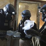 A U.N. chemical weapons expert, wearing a gas mask, holds a plastic bag containing samples from one of the sites of an alleged chemical weap A U.N. chemical weapons expert, wearing a gas mask, holds a plastic bag containing samples from one of the sites of an alleged chemical weap
