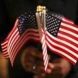 A woman holds a cluster of U.S. flags during a U.S. Citizenship and Immigration Services naturalization ceremony in Oakland, California Augu A woman holds a cluster of U.S. flags during a U.S. Citizenship and Immigration Services naturalization ceremony in Oakland, California Augu