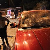 People stand near a SUV vehicle with a broken windshield after protesters threw stones at the driver who was involved in a hit-and-run accid People stand near a SUV vehicle with a broken windshield after protesters threw stones at the driver who was involved in a hit-and-run accid