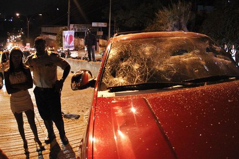 People stand near a SUV vehicle with a broken windshield after protesters threw stones at the driver who was involved in a hit-and-run accid People stand near a SUV vehicle with a broken windshield after protesters threw stones at the driver who was involved in a hit-and-run accid
