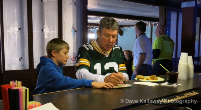 Lynn Dickey signing something for a young Packer fan at the VIP party at Club 64...