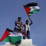 Palestinians hold national flags as they celebrate after an announcement of a reconciliation agreement in Gaza City April 23, 2014. REUTERS/ Palestinians hold national flags as they celebrate after an announcement of a reconciliation agreement in Gaza City April 23, 2014. REUTERS/