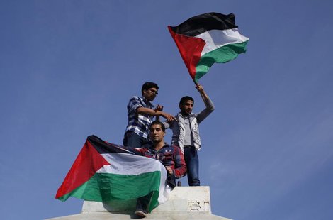 Palestinians hold national flags as they celebrate after an announcement of a reconciliation agreement in Gaza City April 23, 2014. REUTERS/ Palestinians hold national flags as they celebrate after an announcement of a reconciliation agreement in Gaza City April 23, 2014. REUTERS/