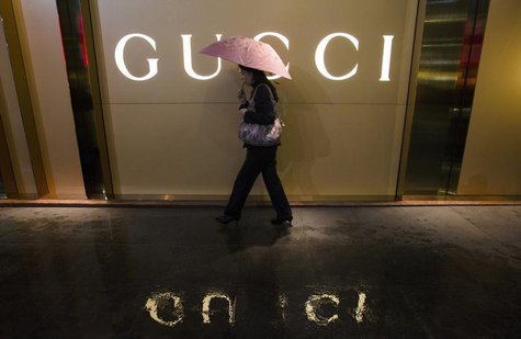 A woman holding an umbrella walks past a company logo of a Gucci boutique outside a shopping mall amid rainfall in central Guangzhou, Guangd A woman holding an umbrella walks past a company logo of a Gucci boutique outside a shopping mall amid rainfall in central Guangzhou, Guangd