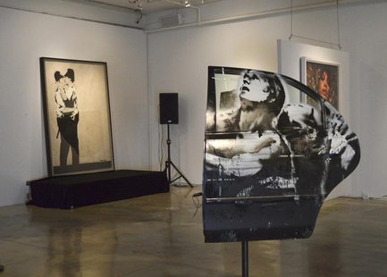 Paintings titled "Crazy Horse Car Door" and in the background, "Kissing Coppers", by the British street artist Banksy, are seen on display a Paintings titled "Crazy Horse Car Door" and in the background, "Kissing Coppers", by the British street artist Banksy, are seen on display a