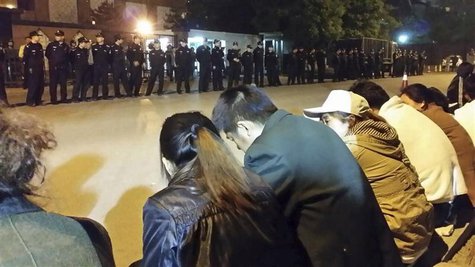 Family members (front) of passengers aboard missing Malaysia Airlines flight MH370 gather for a sit-in protest as security personnel stand g Family members (front) of passengers aboard missing Malaysia Airlines flight MH370 gather for a sit-in protest as security personnel stand g