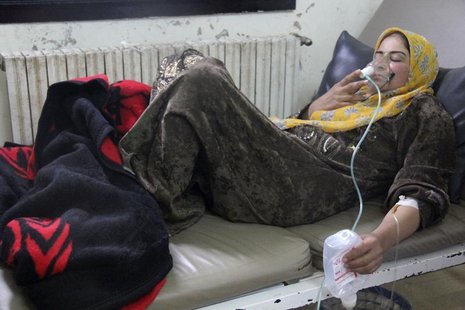 A woman, affected by what activists say was a gas attack, breathes through an oxygen mask inside a field hospital in Kfar Zeita village in t A woman, affected by what activists say was a gas attack, breathes through an oxygen mask inside a field hospital in Kfar Zeita village in t