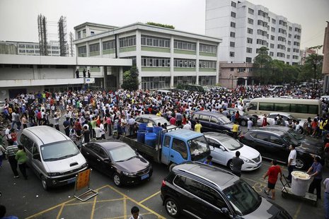 Workers protest during a strike as police stand guard at the factory area of Yue Yuen Industrial, in Dongguan, Guangdong province April 18, Workers protest during a strike as police stand guard at the factory area of Yue Yuen Industrial, in Dongguan, Guangdong province April 18,