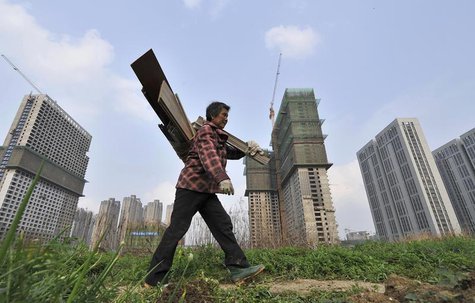 A garbage collector walks past residential and office buildings in construction, in Hefei, Anhui province, April 3, 2014. REUTERS/Stringer A garbage collector walks past residential and office buildings in construction, in Hefei, Anhui province, April 3, 2014. REUTERS/Stringer