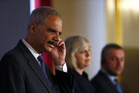 (From L to R) U.S. Attorney General Eric Holder scratches his ear as he answers a question during a news conference with Britain's Home Secr (From L to R) U.S. Attorney General Eric Holder scratches his ear as he answers a question during a news conference with Britain's Home Secr