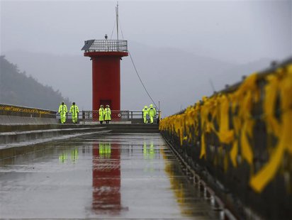 Police officers stand guard at a pier, as yellow ribbons dedicated to missing and dead passengers on board the capsized Sewol ferry are tied Police officers stand guard at a pier, as yellow ribbons dedicated to missing and dead passengers on board the capsized Sewol ferry are tied
