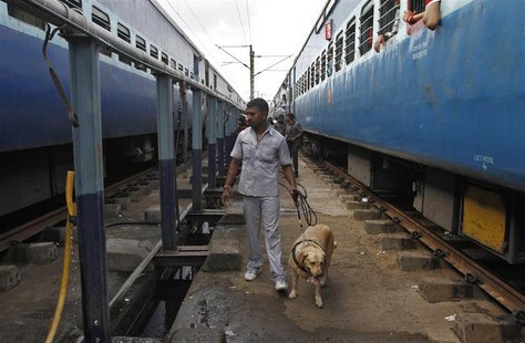 A member of a bomb disposal squad with a sniffer dog examines a passenger train (L) in which two explosions occurred, at the railway station A member of a bomb disposal squad with a sniffer dog examines a passenger train (L) in which two explosions occurred, at the railway station