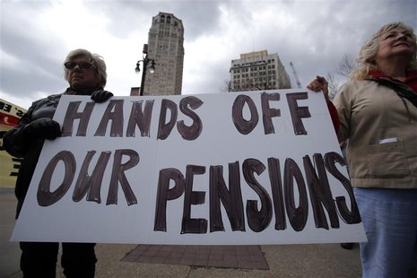 Two protestors hold a sign during a May Day protest against the Detroit Emergency Manager and the municipal Bankruptcy in downtown Detroit, Two protestors hold a sign during a May Day protest against the Detroit Emergency Manager and the municipal Bankruptcy in downtown Detroit,