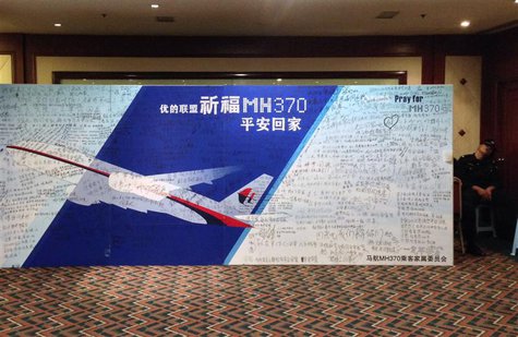 A policeman takes a nap beside a board written with messages for passengers onboard the missing Malaysia Airlines Flight MH370 during a clos A policeman takes a nap beside a board written with messages for passengers onboard the missing Malaysia Airlines Flight MH370 during a clos
