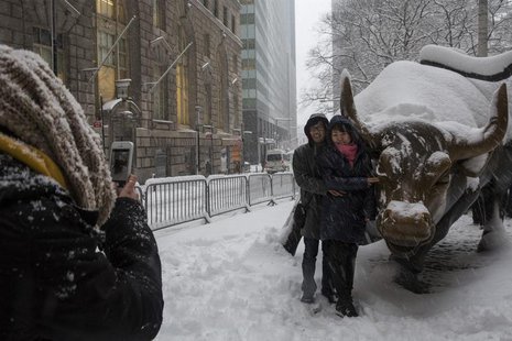 Tourists pose for a photo with the Charging Bull during a morning snow in New York's financial district near Wall Street February 13, 2014. Tourists pose for a photo with the Charging Bull during a morning snow in New York's financial district near Wall Street February 13, 2014.