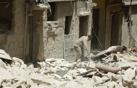 A man stands on debris of damaged buildings at a site hit by what activists said were barrel bombs dropped by forces loyal to Syria's Presid A man stands on debris of damaged buildings at a site hit by what activists said were barrel bombs dropped by forces loyal to Syria's Presid