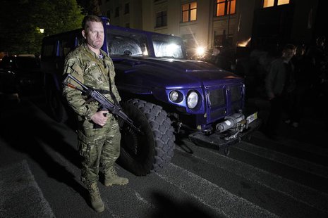 An armed pro-Russian activist stands beside a "Tigr" light armoured vehicle, which was a donation from the Liberal Democratic Party of Russi An armed pro-Russian activist stands beside a "Tigr" light armoured vehicle, which was a donation from the Liberal Democratic Party of Russi