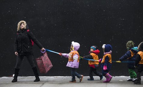 A schoolteacher, attempts to catch snowflakes while leading her students to a library from school in the Harlem neighborhood, located in the A schoolteacher, attempts to catch snowflakes while leading her students to a library from school in the Harlem neighborhood, located in the