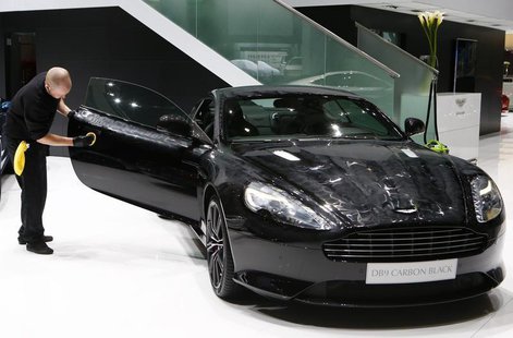 An employee applies wax to Aston Martin DB9 Coupe Carbon Black edition ahead of the 84th Geneva Motor Show at the Palexpo Arena in Geneva Ma An employee applies wax to Aston Martin DB9 Coupe Carbon Black edition ahead of the 84th Geneva Motor Show at the Palexpo Arena in Geneva Ma