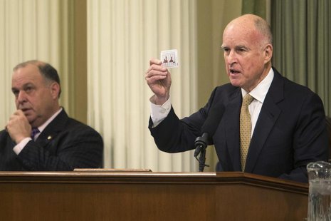 California Governor Jerry Brown holds a playing card detailing the state's fluctuating budgets during his State of the State address at the California Governor Jerry Brown holds a playing card detailing the state's fluctuating budgets during his State of the State address at the