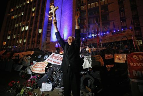 A man holds a cross and a telephone as he stands near a barricade erected by pro-Russian activists during a rally to mark and celebrate the A man holds a cross and a telephone as he stands near a barricade erected by pro-Russian activists during a rally to mark and celebrate the