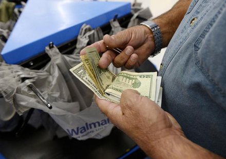 A customer counts his cash at the checkout lane of a Walmart store in the Porter Ranch section of Los Angeles November 26, 2013. REUTERS/Kev A customer counts his cash at the checkout lane of a Walmart store in the Porter Ranch section of Los Angeles November 26, 2013. REUTERS/Kev