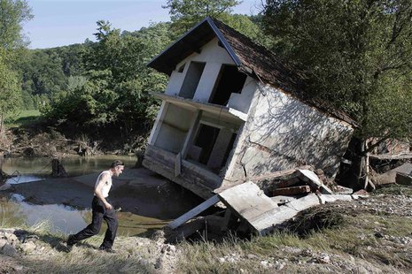 A man walks past a house tilted by floods in the town of Valjevo, southwest from Belgrade May 21, 2014. Picture taken May 21. REUTERS/Marko A man walks past a house tilted by floods in the town of Valjevo, southwest from Belgrade May 21, 2014. Picture taken May 21. REUTERS/Marko