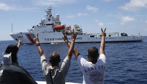 Philippine Marines and a local television reporter (L) gesture towards a Chinese Coast Guard vessel, which twice attempted to block a Philip Philippine Marines and a local television reporter (L) gesture towards a Chinese Coast Guard vessel, which twice attempted to block a Philip