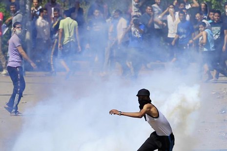 A student, supporting the Muslim Brotherhood and ousted President Mohamed Mursi, throws a tear gas canister, which was earlier launched by r A student, supporting the Muslim Brotherhood and ousted President Mohamed Mursi, throws a tear gas canister, which was earlier launched by r