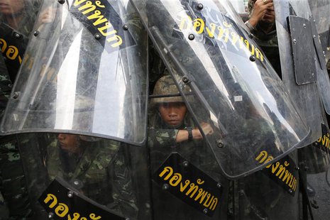 A soldier looks out from behind shields as they take up position to block protestors at a shopping district in central Bangkok May 25, 2014. A soldier looks out from behind shields as they take up position to block protestors at a shopping district in central Bangkok May 25, 2014.