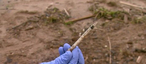 A drug needle is found while cleaning up Red Arrow Park in Marinette on June 25, 2014. (Photo from: FOX 11/YouTube). A drug needle is found while cleaning up Red Arrow Park in Marinette on June 25, 2014. (Photo from: FOX 11/YouTube).