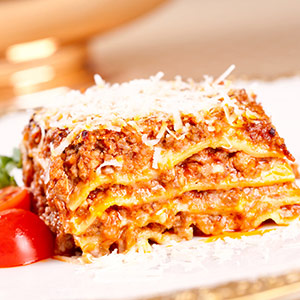 Plate of lasagna with tomato garnish.
