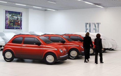 Women walk past Fiat cars under covers at a dealership in Rome October 30, 2012. REUTERS/Alessandro Bianchi